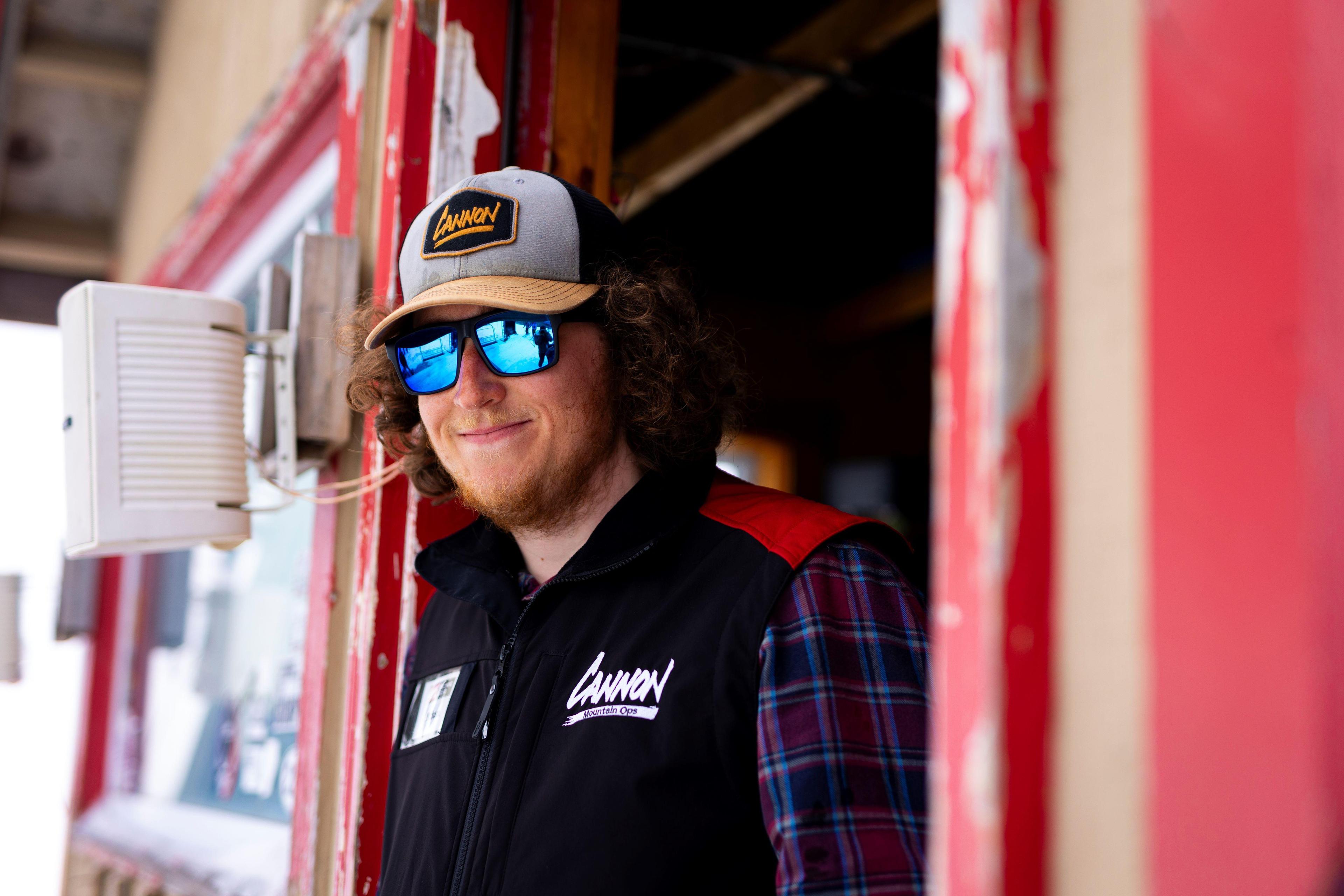 Lift attendant wearing cannon trucker hat and cannon vest