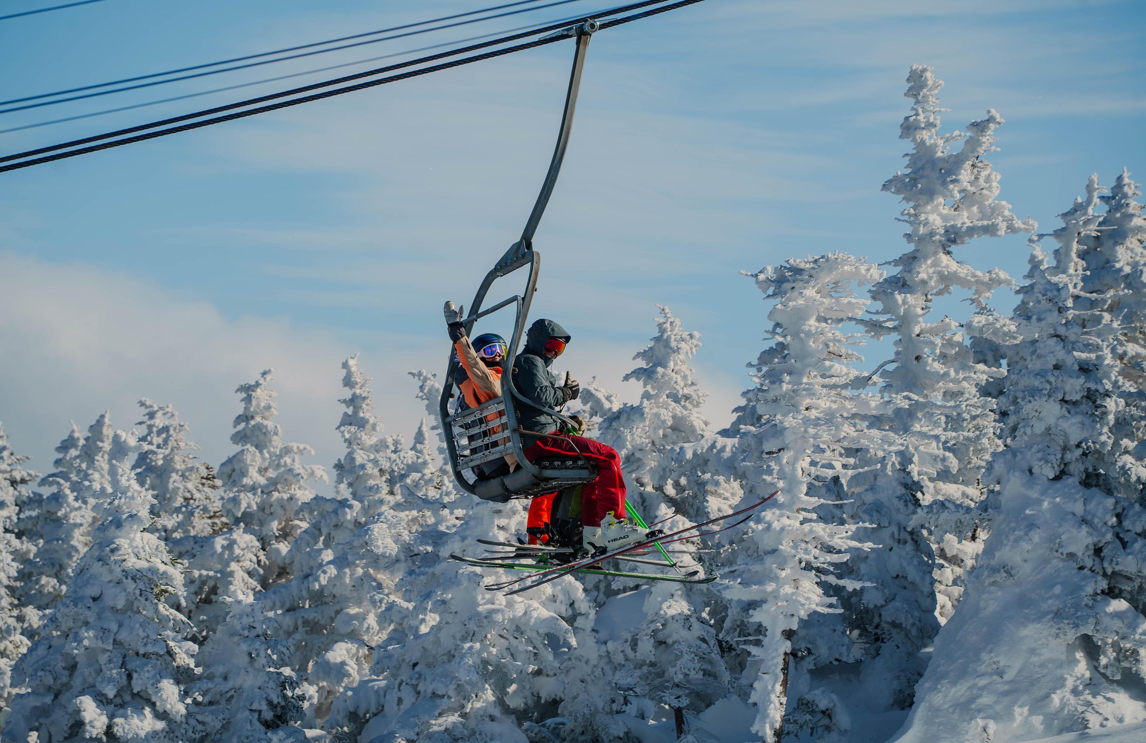 Skiers on lift waving, snowy background