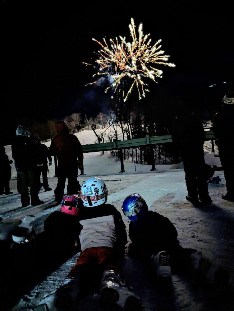 Kids lay on the ground watching fireworks.