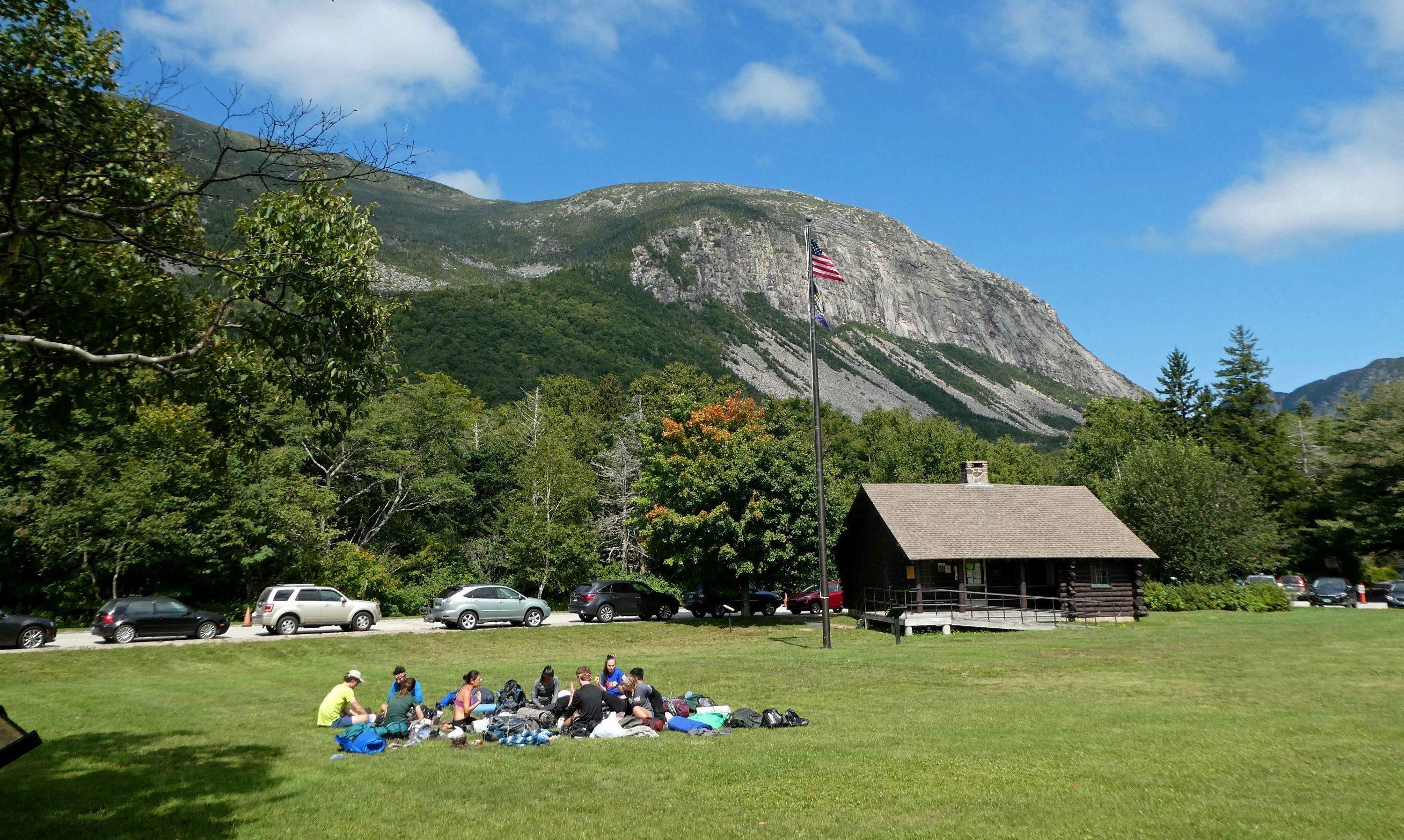 group of kids in front of the hiker cabin with cannon cliff in the background