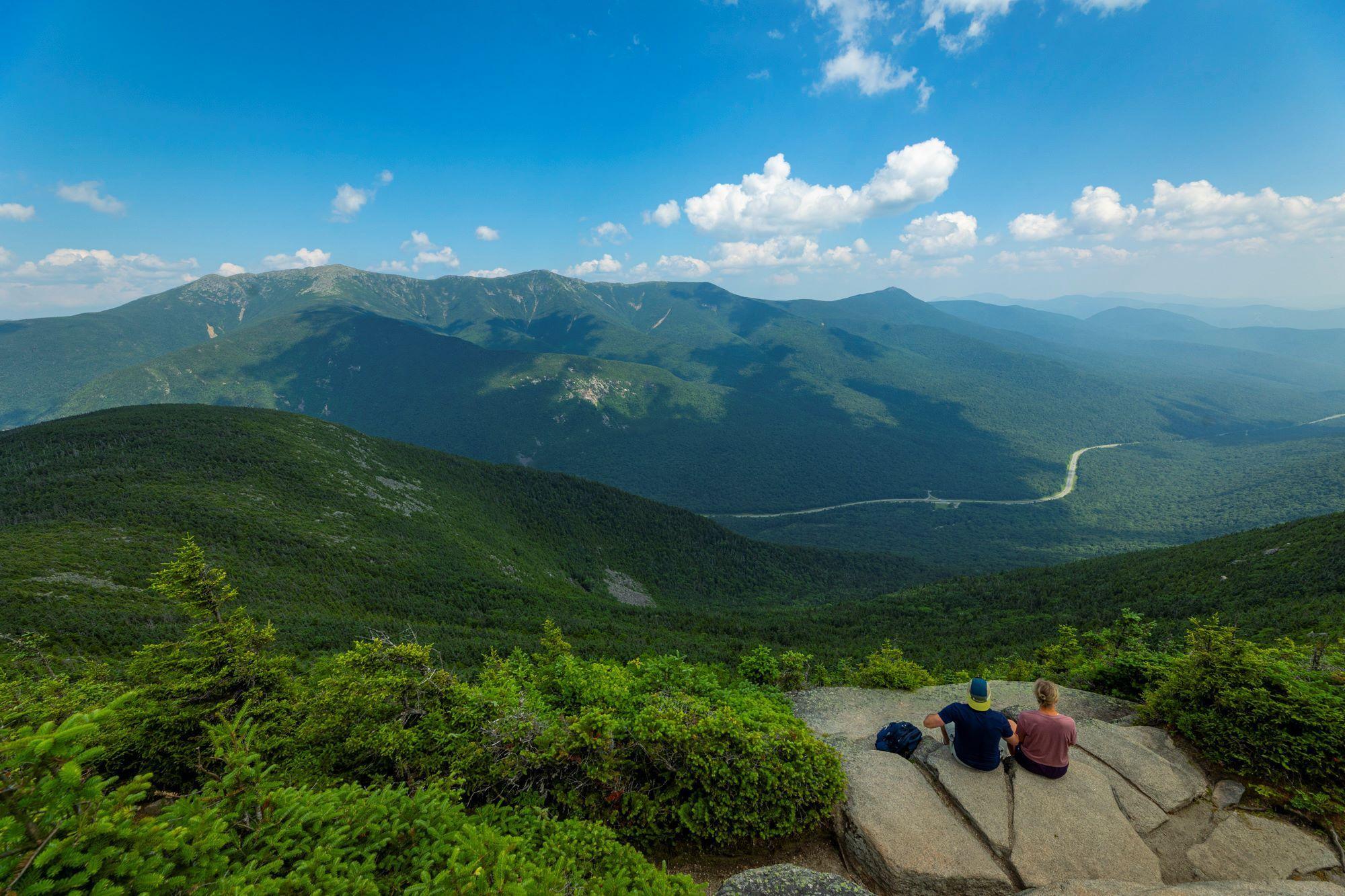 Young couple sits on rocks while enjoying the view