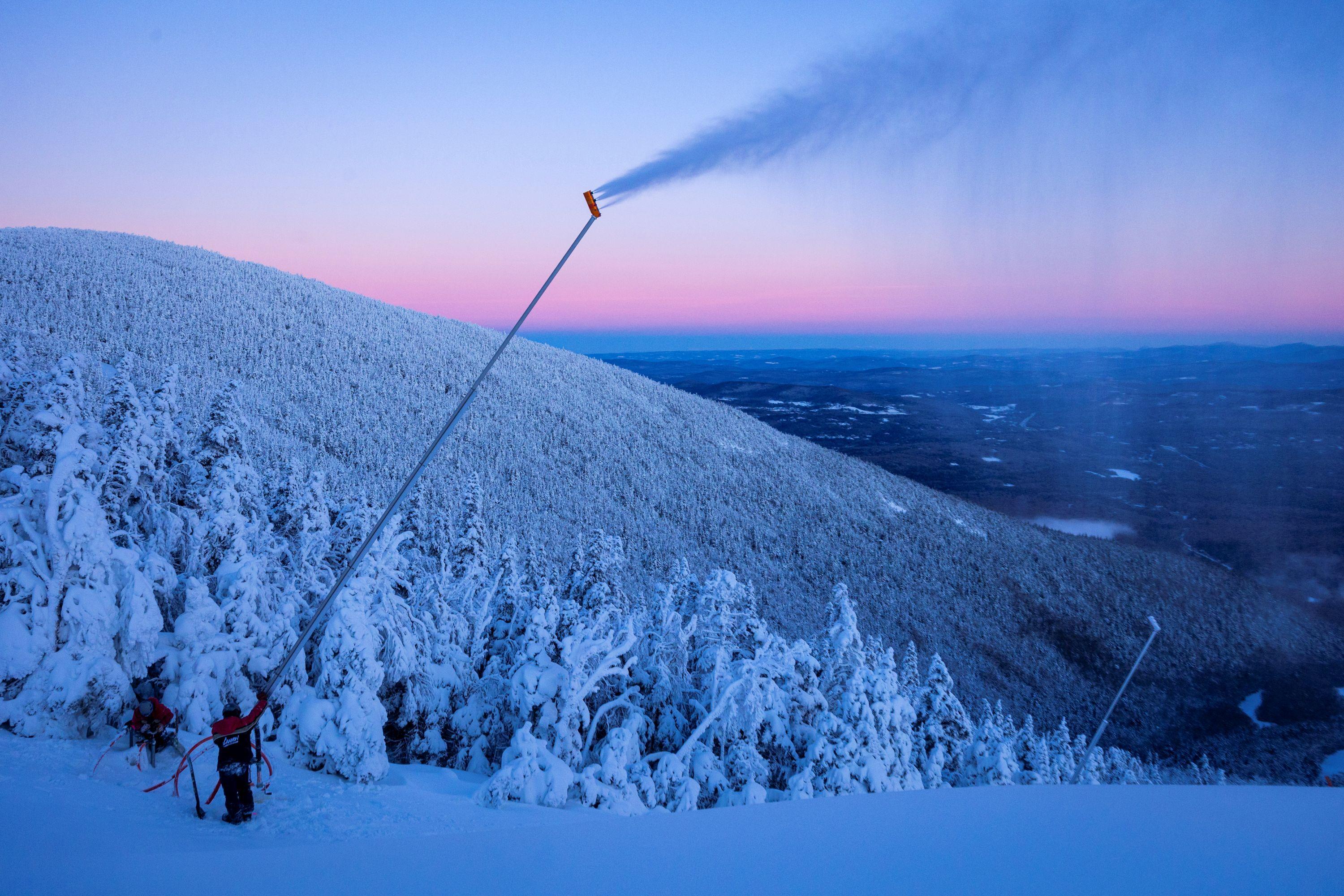A snowmaker works on a tower gun as at the summit of cannon as the sunrises.